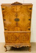 A chest on chest style drinks cabinet with carved detail to top and bottom on cabriole legs (