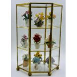 A gilded display cabinet filled with hand painted flower arrangements of biscuit porcelain