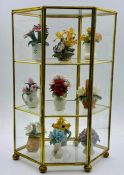A gilded display cabinet filled with hand painted flower arrangements of biscuit porcelain
