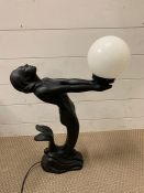 An Art Deco lamp of a mermaid holding a ball