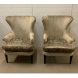 A pair of contemporary wing back chairs with sleek design to arms on ebony style legs