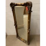 A carved and giltwood wall mirror with scrolled floral leaf to corner (46cm x 105cm)