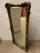 A carved and giltwood wall mirror with scrolled floral leaf to corner (46cm x 105cm)