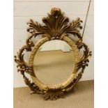 A 20th century giltwood oval mirror with floral carving
