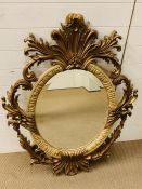 A 20th century giltwood oval mirror with floral carving