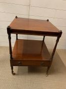 A mahogany two tier side table terminating in brass castors