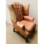 A George II style wing armchair with leather upholstered and deep button back over a loose cushion