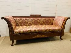 A classical style settee with out scrolled arms upholstered seat over a carved frame ending in