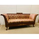 A classical style settee with out scrolled arms upholstered seat over a carved frame ending in