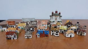 A collection of twenty eight collectable miniature ceramic and pottery hand painted houses, made