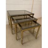 A nest of brass frame tables with smoked glasses and reeded legs ( Largest 56 cm x 46cm x46cm)