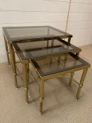 A nest of brass frame tables with smoked glasses and reeded legs ( Largest 56 cm x 46cm x46cm)