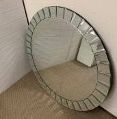 A large circular mirror with small decorative mirror with small decorative mirrors to edge (