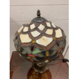 A Tiffany style table lamp with cream, green floral design to shade with a patinated bronze style