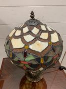 A Tiffany style table lamp with cream, green floral design to shade with a patinated bronze style