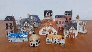 A collection of thirteen collectable miniature ceramic and pottery hand painted houses, made in