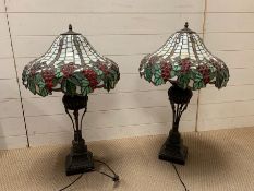 A pair of Tiffany style lamps with grapes and vines design to shade with a patinated bronze style