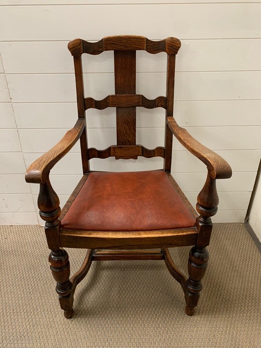 An oak open armchair with oxblood seat cushion