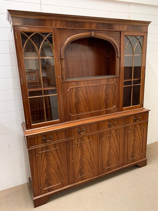 A mahogany display unit with drop down drinks cabinet and four panel cabinets below