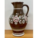 A substantial pottery pitcher or jug with floral decoration on brown grounds, 41 cm high by Gmundner