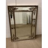 An ornate wall mirror with additional mirrored boarder and scroll work to corner
