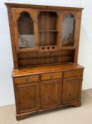 A pine dresser with glazed doors to top and cupboards to base (H190cm W133cm D45cm)