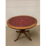 An oval side table with leather top on splayed feet (H53cm W47cm)