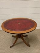 An oval side table with leather top on splayed feet (H53cm W47cm)