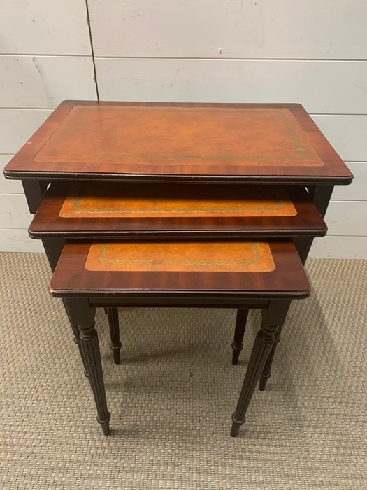 A nest of three tables with reeded legs and leather top (56cm x 36cm largest)