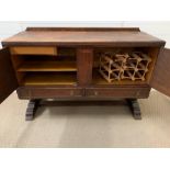 An oak sideboard with brass fittings and doors opening to reveal cutlery drawer and shelves
