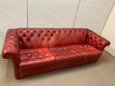 A large three seater vintage red leather chesterfield sofa (H65cm W220cm D82cm seat H41cm)