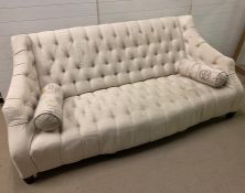 A three seater cream button back sofa