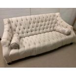 A three seater cream button back sofa