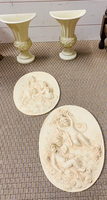 Two white vases and two cherub themed plaques.