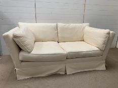 A two seater cream sofa with removable covers and cushions