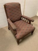 A Victorian mahogany salon gentleman's chair with foliate carving and baluster turning on castors