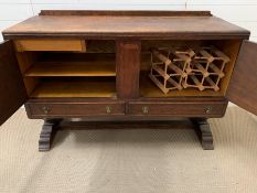 An oak sideboard with brass fittings and doors opening to reveal a cutlery drawer and shelves