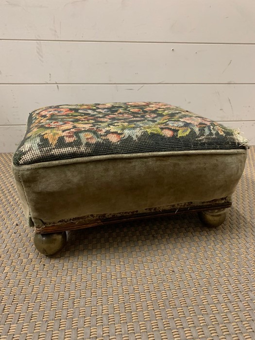 A tapestry footstool on brass bun feet