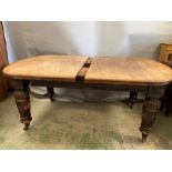 A Victorian mahogany extending dining table with turned and reeded legs ending in castors, one extra