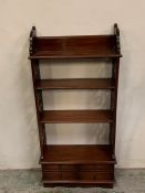 A waterfall style bookcase with four small drawers to bottom.