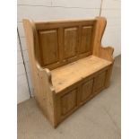 A small pine pew with three panel back with lidded seat and storage under (H90cm W92cm D37cm)