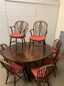 A large oak gate leg circular table with two carvers and six wheel back chairs