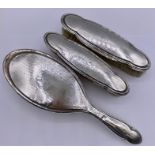 A selection of three silver backed items from a dressing table set.