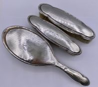 A selection of three silver backed items from a dressing table set.