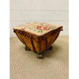 A tapestry foot stool with brass lion paw feet