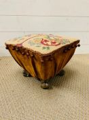 A tapestry foot stool with brass lion paw feet