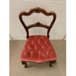 A mahogany dining chair with pink button back seat pad