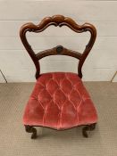 A mahogany dining chair with pink button back seat pad