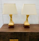 A pair of contemporary table lamps with twisted centre on wooden base and cream shades