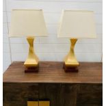 A pair of contemporary table lamps with twisted centre on wooden base and cream shades